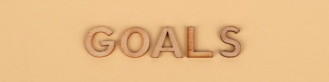 Wooden letters spelling 'GOALS' on a plain background, emphasizing motivation.